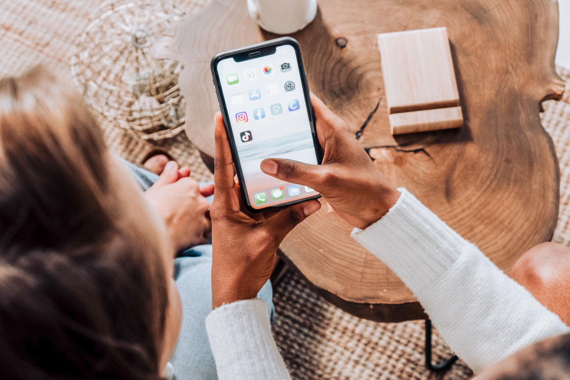 couple sitting by the table with a man holding his phone - featured image for UK travel apps