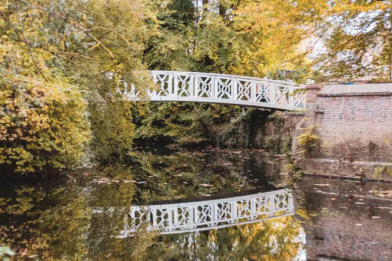 White bridge among the trees over the River Great Ouse leading to Holt Island Nature Reserve