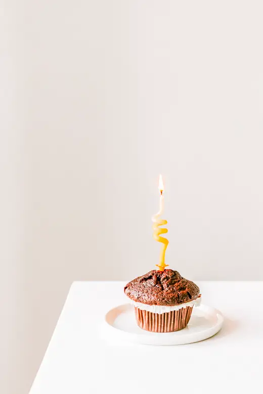 Cupcake with a lighted candle sitting on a white table - my first blogiversary, 7 things I wish I knew before starting a blog