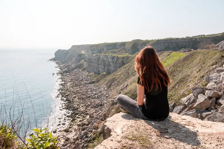 Me sitting on the cliff edge looking at the sea - featured image for weekend in Weymouth