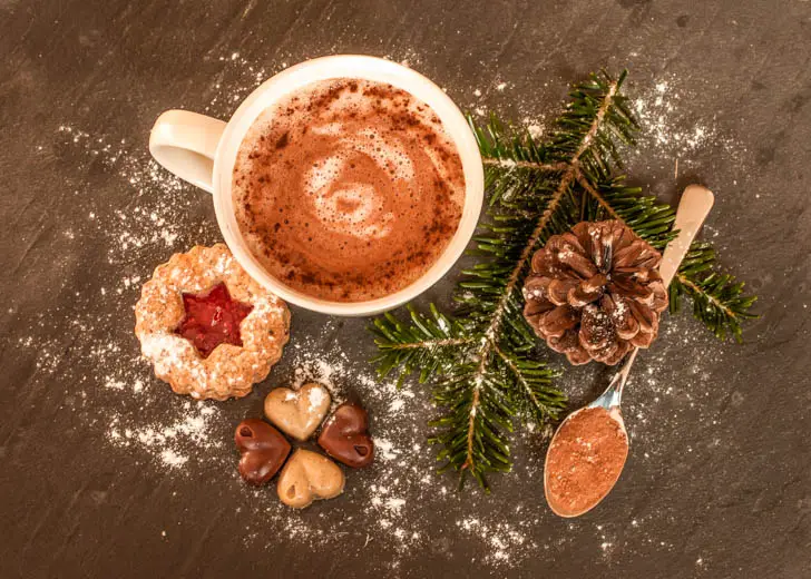 View from above of the cup of hot chocolate, biscuits and festive decoative items around them - how to get into the Christmas spirit