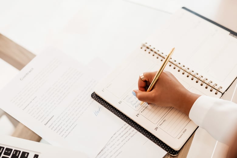 Bird view of a woman writing in a calendar - featured image for content writing topics