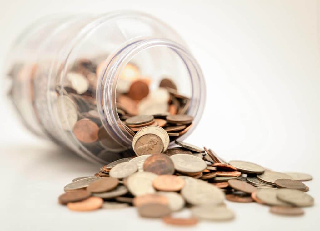 jar lying on the table with pennies in it - UK travel apps for dealing with money