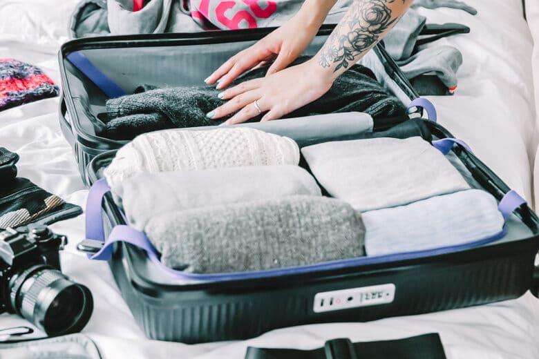 Women putting rolled up clothes into the suitcase