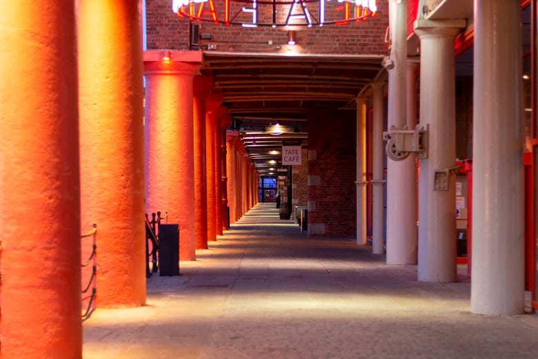Cost of living in Liverpool - alleway with red columns in by Tate Liverpool, Albert Dock