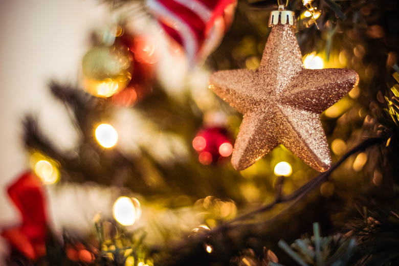 Close up of decorations hanging on the Christmas tree with white star at the front - featured image for how to get into the Christmas spirit